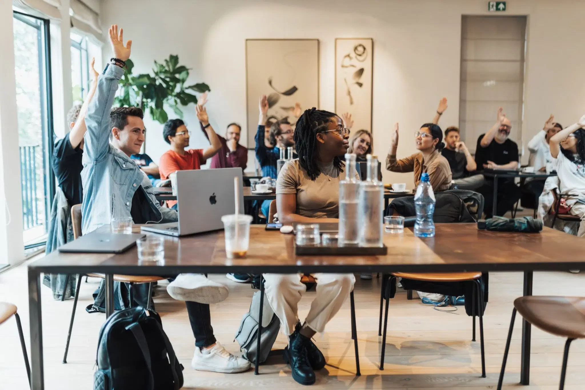 A group of adults with hands raised during an interactive session.