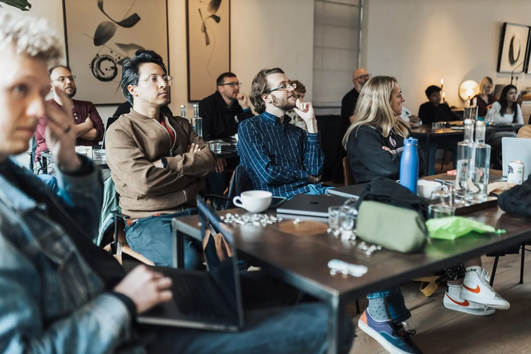 People seated around a long table in a modern room, listening.